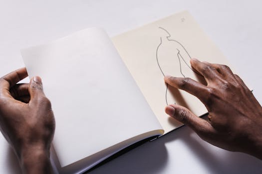 Close-up of hands interacting with a tactile art drawing on a sketchbook page.