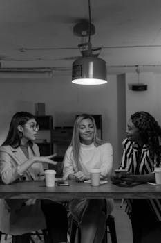 Three diverse businesswomen engaged in a collaborative meeting at a table, fostering creative ideas.