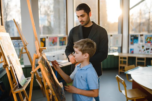 Art teacher supervises child painting in a well-lit classroom, promoting creativity.